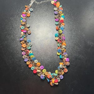 May include: A colorful necklace with small, round, wooden beads in various colors, including orange, purple, green, and blue. The beads are strung on a copper-colored chain and connected to a silver-colored chain clasp.