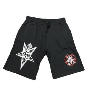 May include: Black shorts with a drawstring waist and two pockets. The shorts feature a white pentagram graphic on the left leg and a red and white graphic on the right leg. The shorts are made of a soft material.
