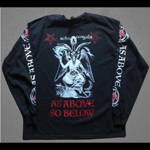 May include: Black long-sleeve shirt with a graphic of a horned figure, the text "AS ABOVE SO BELOW", and the words "AS ABOVE" on the sleeves. The shirt has a red and white design.