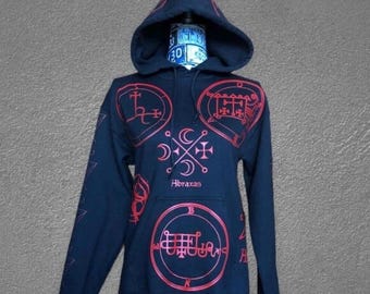 Puede incluir: Una sudadera con capucha azul marino con sigilos rojos y la palabra "Abraxas" impresa en la parte delantera. La sudadera tiene una capucha con cordón y un bolsillo de canguro. Las mangas tienen un diseño de estrella.