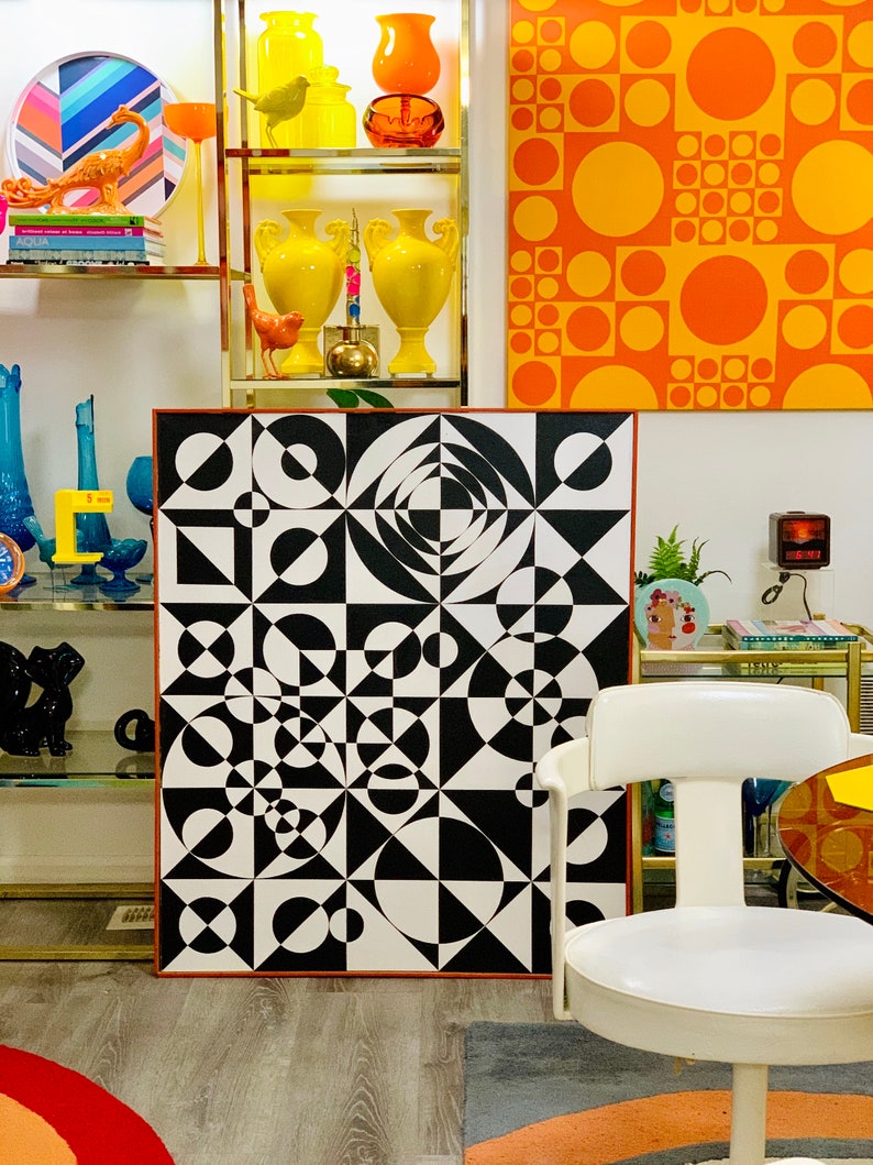 May include: A black and white geometric abstract art print with circles, squares, and triangles. The print is framed in a thin, brown wood frame.