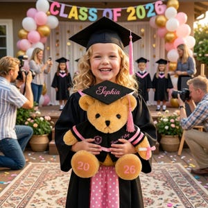 Puede incluir: Una ni&ntilde;a sonriente con birrete y toga de graduaci&oacute;n sostiene un oso de peluche, tambi&eacute;n con atuendo de graduaci&oacute;n. El oso tiene los n&uacute;meros "20" y "26" en sus patas. El fondo incluye globos y el texto "CLASS OF 2026".