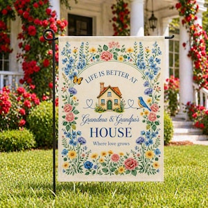 May include: A garden flag with the text "Life is Better at Grandma & Grandpa's House" surrounded by a floral wreath. The flag features a house illustration, a bluebird, and a butterfly, with a green and yellow color scheme.