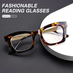 May include: Reading glasses with a brown and black tortoiseshell pattern frame and clear lenses. The text FASHIONABLE READING GLASSES and VERSATILE TRENDY is visible in the upper left corner. The glasses feature a thick, angular frame design.