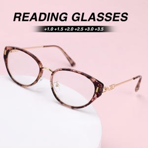 May include: Reading glasses with a brown tortoiseshell pattern frame, thin gold-tone metal temples, and clear lenses. The text READING GLASSES and the magnification strengths +1.0 +1.5 +2.0 +2.5 +3.0 +3.5 are displayed above the eyewear.