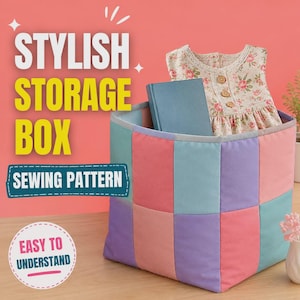 May include: A square fabric storage box featuring a patchwork design of pastel pink, purple, and light blue rectangular panels. Inside the box sits a blue book and a sleeveless dress with a floral pattern and three brown buttons on the front.