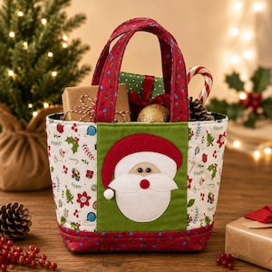 May include: A quilted fabric tote bag featuring a central green panel with a Santa Claus applique. The bag has red handles and side panels patterned with Christmas trees, holly, and ornaments. It is filled with wrapped gifts and a candy cane.