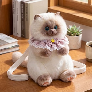 Peut inclure: Sac en peluche en forme de chat crème, avec des pattes marron et un col en dentelle rose. Le chat a des yeux bleus et un bouton jaune sur le col. Le sac a une sangle crème.