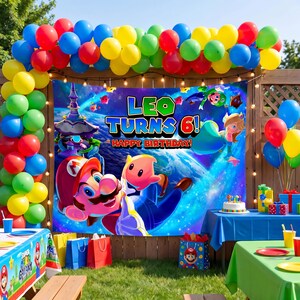 May include: A rectangular birthday party backdrop featuring Mario and Rosalina in space with the text LEO TURNS 6! HAPPY BIRTHDAY. The banner is framed by a colourful balloon arch in red, blue, yellow, green, and pink, with tables below.
