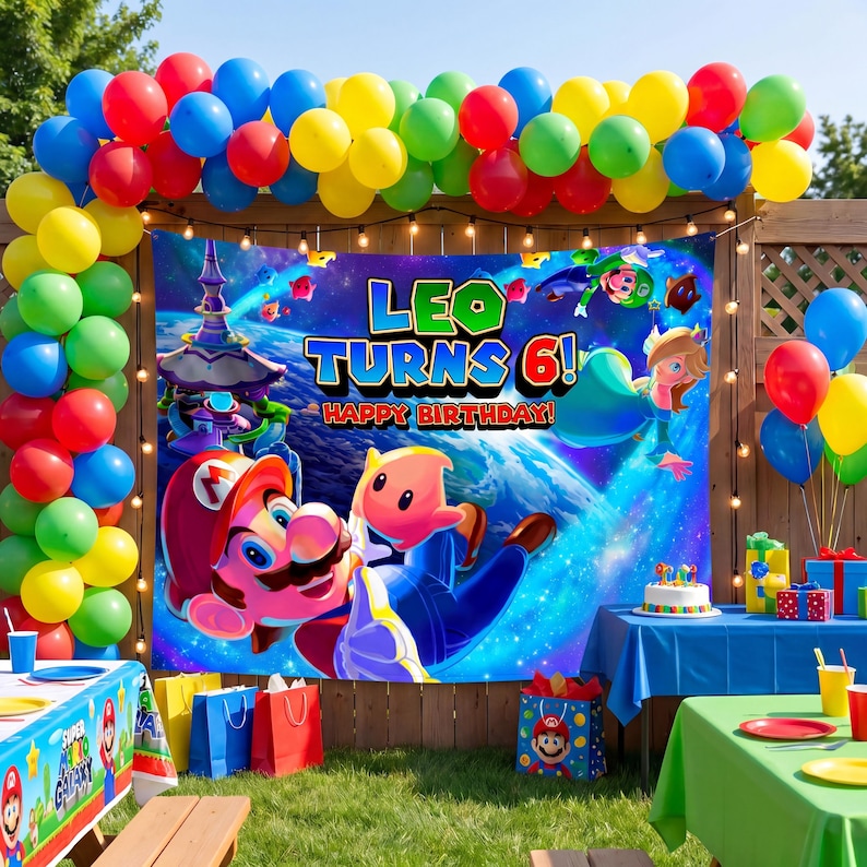 May include: A rectangular birthday party backdrop featuring Mario and Rosalina in space with the text LEO TURNS 6! HAPPY BIRTHDAY. The banner is framed by a colourful balloon arch in red, blue, yellow, green, and pink, with tables below.