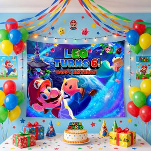 May include: A Super Mario themed birthday party backdrop featuring the text 'LEO TURNS 6! HAPPY BIRTHDAY' with Mario and space characters, surrounded by colourful balloons, streamers, party hats, and two gift boxes on a table.