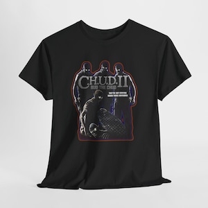 May include: Black t-shirt featuring a graphic from the movie "C.H.U.D. II". The design includes the movie title, the phrase "Bud the Chud", and the tagline "They're not staying down there anymore!" The graphic has a red and blue color scheme.
