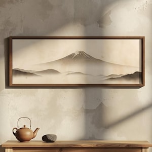 May include: A rectangular framed wall art print featuring a monochromatic ink wash style landscape of Mount Fuji with a snow-capped peak, surrounded by layered misty mountains, displayed in a thin dark wood frame with a neutral beige background.