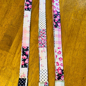 May include: Three colorful fabric lanyards with floral patterns and black accents. Each lanyard has a silver swivel clasp.