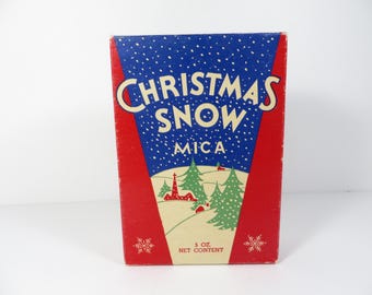 May include: Vintage Christmas Snow Mica box with a red and blue design. The box features the words "Christmas Snow" in white, with a winter scene of trees and a church. The net content is 5 oz.