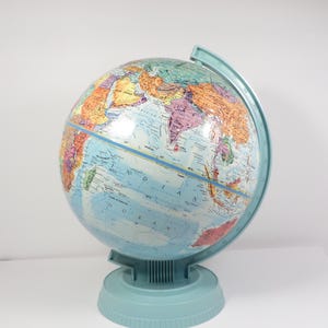 May include: A vintage globe with a light blue base and meridian. The globe features a detailed map with various countries in shades of orange, green, and purple, set against a blue ocean. The globe is a classic educational tool.