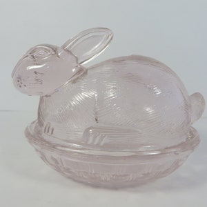 May include: A white ceramic mug with a black handle and the text "But First, Coffee" in a bold, black font. The mug is set against a blurred background, suggesting a cozy setting.