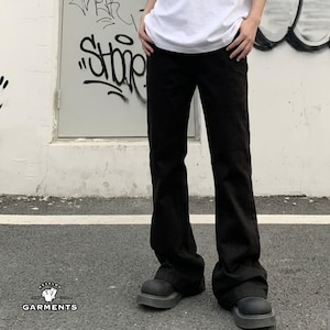 May include: A pair of solid black trousers with a straight-leg cut, paired with a plain white t-shirt and chunky black platform shoes. The trousers feature a clean, minimalist design with a standard waistband and full-length hemline.