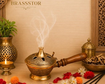 May include: A brass incense burner with a wooden handle, emitting white smoke. The burner has intricate floral patterns and is surrounded by flowers, incense sticks, and a small candle holder. The text "BRASSTOR" is visible.