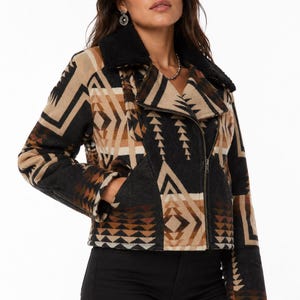 May include: A cropped moto-style jacket featuring a geometric pattern in shades of black, tan, and brown. The jacket includes a black faux-shearling collar, a diagonal front zipper closure, long sleeves, and two side pockets with a structured fit.