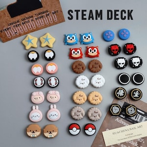May include: A selection of Steam Deck thumb grips in various designs, including stars, cartoon characters, skulls, and geometric patterns. The text "STEAM DECK" is displayed in large, bold letters.