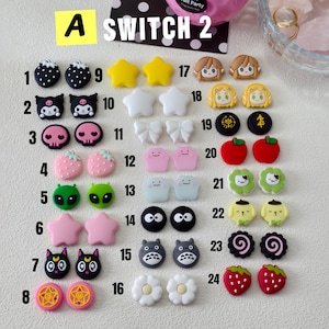 May include: A collection of colorful, cartoon-style charms, including strawberries, stars, and character faces. The charms are in various colors like pink, yellow, and black. The text "A SWITCH 2" is visible at the top.