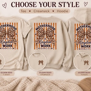 Könnte beinhalten: Ein beiges T-Shirt, ein Rundhals-Sweatshirt und ein Kapuzenpullover mit einem Rückendruck aus einer Leoparden-Schleife und dem Text MOTHERHOOD is KINGDOM WORK PROVERBS 31:25-27 auf orangefarbenen Streifen. Vorne befindet sich jeweils eine kleine Schleife.