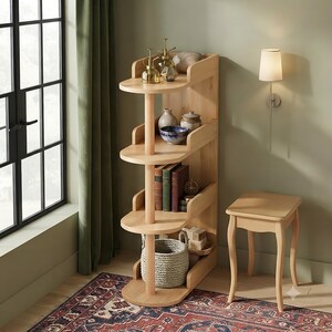 May include: A light-colored wooden four-tier shelving unit with rounded shelves and a central support pillar. The shelves hold various decorative items including glass bottles, ceramic bowls, books, and a woven basket on the bottom shelf.