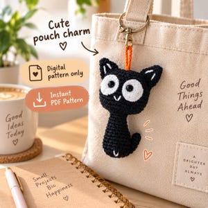 May include: A black and white crocheted cat charm with large white eye patches and a small orange loop, attached to a beige canvas tote bag with a gold metal clasp. The image includes text reading Cute pouch charm, Digital pattern only, and Instant PDF Pattern.