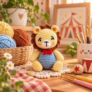 Puede incluir: Un le&oacute;n de peluche tejido a mano con cara amarilla, melena marr&oacute;n y peto azul claro con una peque&ntilde;a pajarita roja. El le&oacute;n est&aacute; sentado sobre un tapete de encaje blanco junto a una cesta llena de ovillos de lana de colores y ganchillos.