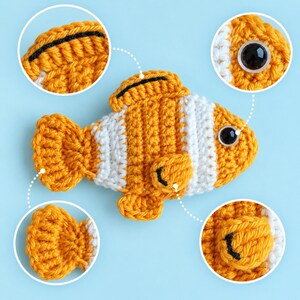 May include: A crocheted clownfish toy featuring vibrant orange and white horizontal stripes, a black-rimmed dorsal fin, a small side fin with black detailing, and a round black plastic eye. Four circular insets highlight the fin and eye details.