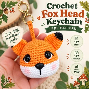 以下が含まれることがあります： かぎ針編みのキツネの頭のキーホルダーのPDFパターン。Crochet Fox Head Keychain PDF PATTERN、Cute little woodland make!、127 STEPS、127 PHOTOS、LEVEL MEDという文字が書かれています。キツネの頭はオレンジと白で、耳と目は黒です。