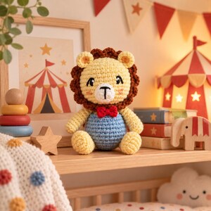 Puede incluir: Un le&oacute;n de peluche tejido a ganchillo con cara de color amarillo p&aacute;lido, melena marr&oacute;n oscuro y cuerpo azul claro. El le&oacute;n tiene una peque&ntilde;a pajarita roja, ojos bordados en negro y un hocico blanco con nariz y boca cosidas en negro.