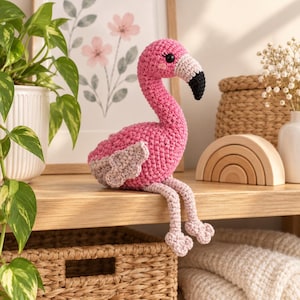 Peut inclure: Un flamant rose en crochet avec un corps rose vif, des pattes rose clair et un bec blanc à pointe noire. Cette peluche présente un long cou courbé, de petits yeux noirs et des ailes texturées, conçue pour tenir assise sur une surface plane.