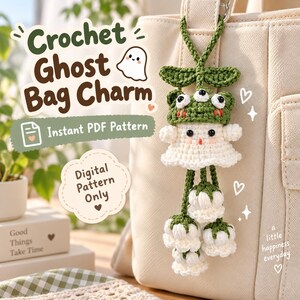 May include: A crochet ghost bag charm featuring a white ghost figure wearing a green frog hat with three eyes, suspended from a green loop. Below the ghost are three white bell-shaped flowers with green stems. Text reads Crochet Ghost Bag Charm.