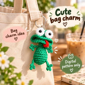 May include: A green crocheted frog bag charm with large white eyes, black pupils, and a red tongue, attached to a metal keyring on a beige canvas tote bag. Text on the image reads: Cute bag charm, Bag charm idea, and Digital pattern only.