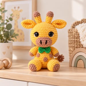 May include: A yellow crochet giraffe toy with brown spots, large black eyes, and a green bow tie. The stuffed animal has two small horns on its head, rounded ears, and a textured tail. It is crafted with yarn in a seated position.