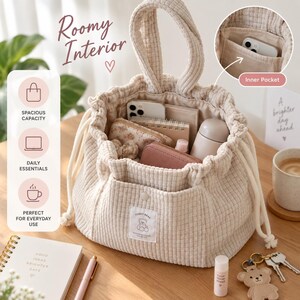 Peut inclure: Un sac &agrave; cordon en tissu textur&eacute; de couleur cr&egrave;me avec une poign&eacute;e sup&eacute;rieure et une poche avant dot&eacute;e d'un petit &eacute;cusson rectangulaire avec une illustration d'ours en peluche et le texte "TEDDY BEAR". L'int&eacute;rieur contient un smartphone.