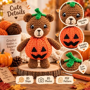May include: A brown crocheted bear toy with a round orange pumpkin-shaped body featuring a black felt jack-o'-lantern face and a green stem on its head. The bear is displayed on a wooden slice, surrounded by yarn balls, a mug, and pumpkins.