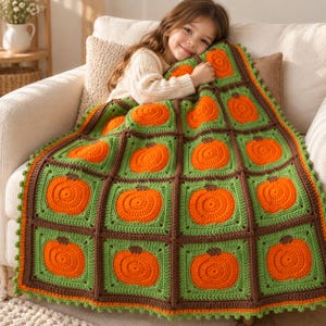 May include: A handmade crochet blanket featuring a grid of square motifs, each displaying a bright orange pumpkin centered on a light green background, framed by dark brown yarn borders and finished with a small green scalloped edge trim.