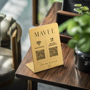 May include: A gold-colored L-shaped metal sign featuring the text MAVEE, a Wi-Fi icon with the text WLAN-ZUGANG, a fork and spoon icon with the text QR-CODE SPEISEKARTE, two QR codes, and the text Schön, dass Sie da sind! with a heart symbol.