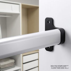Może przedstawiać: Biały drążek do szafy z czarnymi wspornikami montażowymi. Drążek jest zamontowany na białej powierzchni. Tekst "IKEA PAX KOMPLEMENT CLOSET ROD END VIEW" jest widoczny na dole.