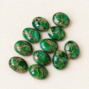May include: A collection of eleven polished, oval-shaped stones featuring a vibrant emerald green colour with intricate, metallic copper-coloured veining running throughout the surface of each individual piece, creating a distinct cracked pattern.