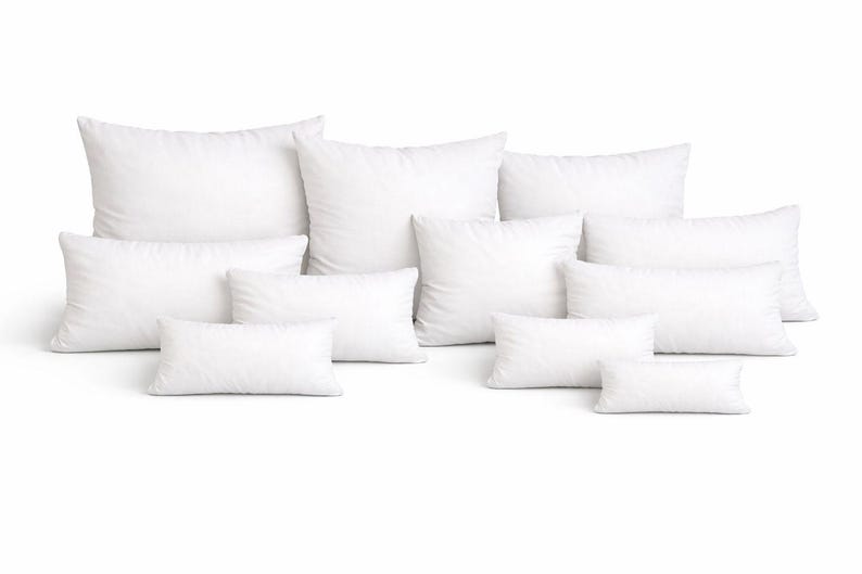 May include: A collection of white pillows in various sizes and shapes, including square and rectangular. The pillows are arranged on a white background, showcasing their fluffy appearance. Ideal for home decor and bedding.