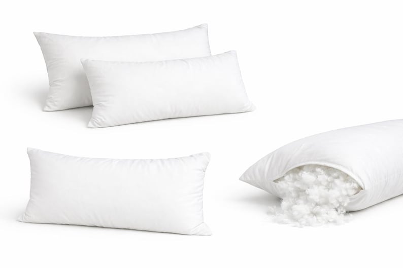 May include: Several white rectangular pillows are displayed, with one cut open to reveal the fluffy filling. The pillows are made of a smooth, white fabric and are designed for comfort and support. The image showcases the pillows' shape and construction.