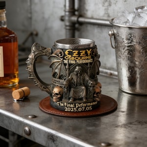 May include: A detailed, bronze-colored stein with the text "OZZY OSBOURNE THE FINAL PERFORMANCE" and the date 2025.07.05. The mug features a handle, skulls, and a seated figure. It rests on a brown leather coaster.