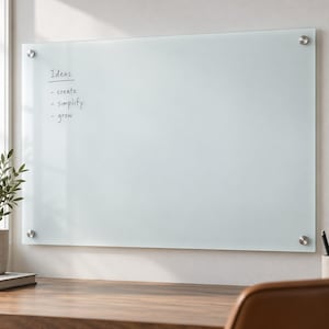 May include: A rectangular frosted glass dry-erase board mounted with four silver circular standoffs. The surface features the handwritten text Ideas, create, simplify, and grow in black ink on the left side of the board.