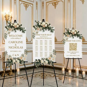 May include: Three white wedding signs with floral arrangements and black easels. The signs read "Welcome," "Find Your Seat," and "Share the Love." The wedding date is September 12, 2024. The signs are decorated with flowers and greenery.