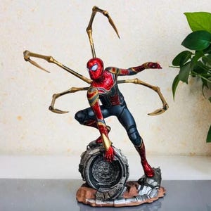 K&ouml;nnte beinhalten: Detaillierte Figur von Spider-Man in dynamischer Pose, mit rotem und goldenem Anzug und mehreren mechanischen Armen. Die Figur steht auf einem metallischen Sockel mit braunem und grauem Gel&auml;nde.