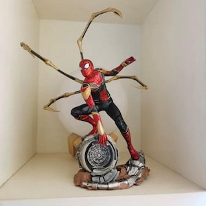 K&ouml;nnte beinhalten: Detaillierte Figur von Spider-Man in dynamischer Pose, mit rotem und goldenem Anzug und schwarzen Akzenten. Die Figur kniet auf einem detaillierten Sockel mit mechanischen Elementen und goldenen Spinnenarmen.